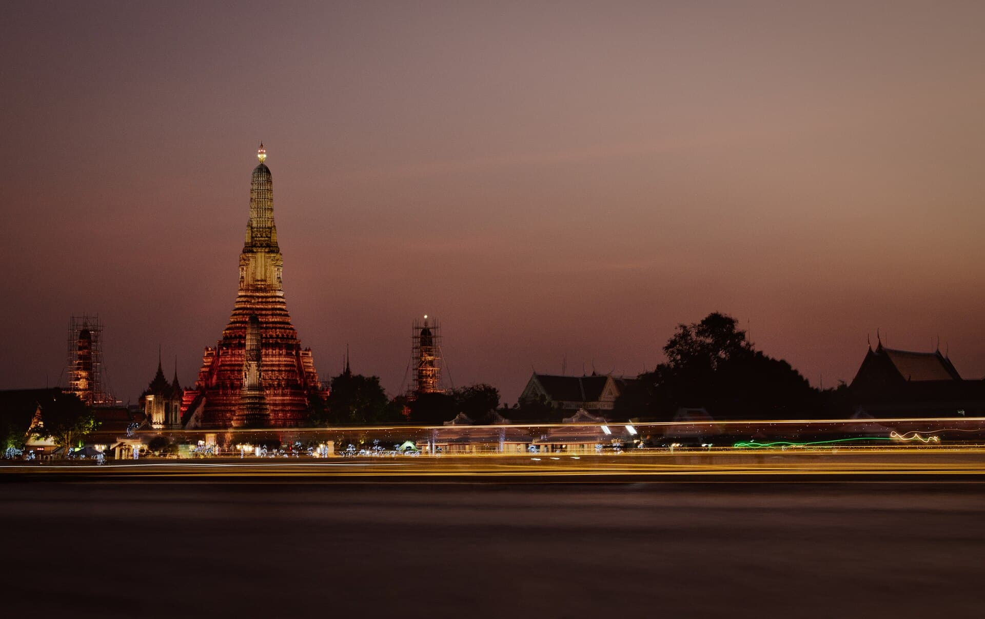 Wat Arun illuminated beside Bangkok’s Chao Phraya River at dusk